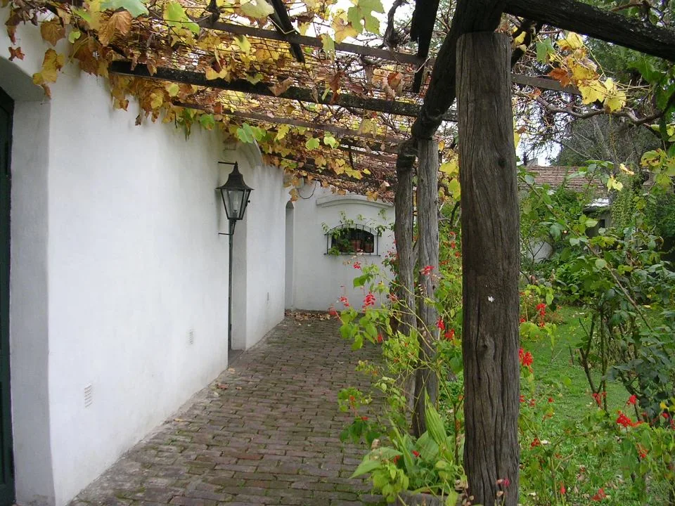 Galería con parra y sendero de ladrillos de la Casa de Haedo